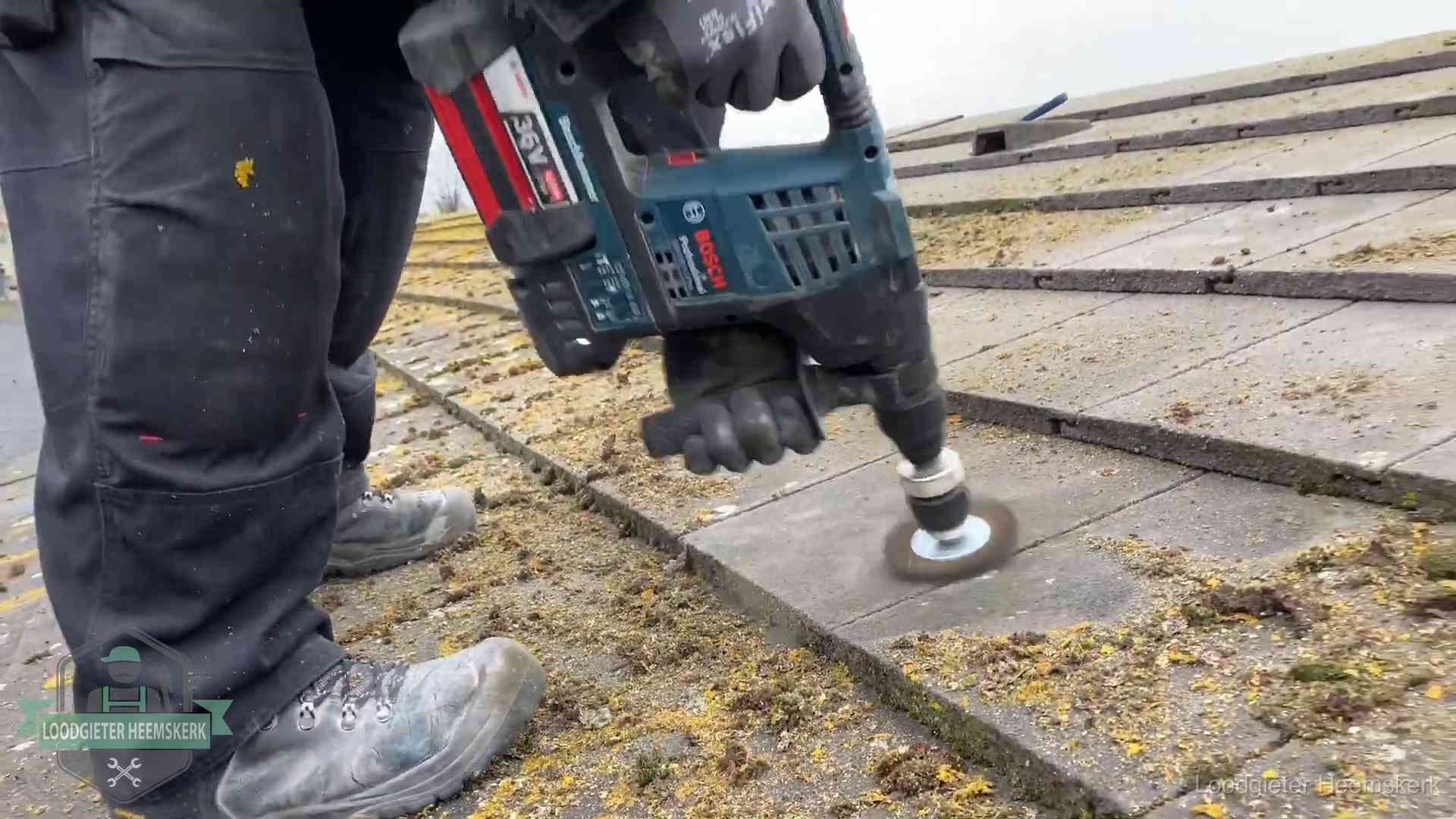 Betonnen dakpannen worden machinaal gereinigd tijdens dakonderhoud in Heemskerk