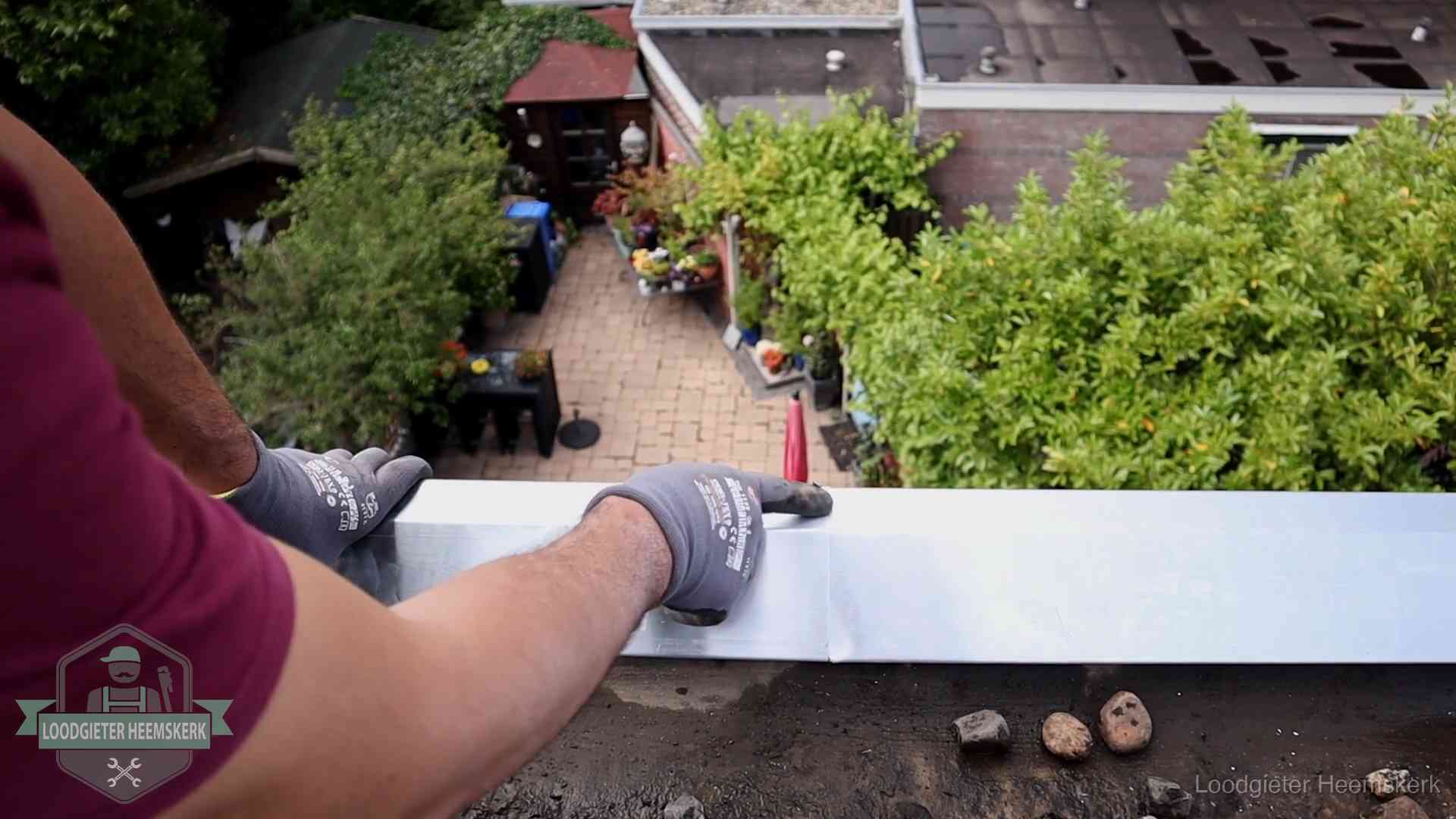 Vakman plaatst een daktrim op de dakrand van een woning in Heemskerk