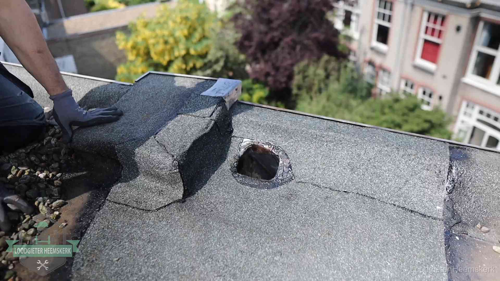 Loodgieter inspecteert een beschadigd bitumen plat dak tijdens een daklekkage-inspectie in Heemskerk