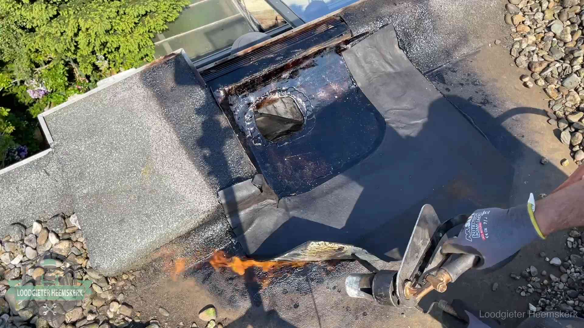 Dakdekker brandt bitumen rond een doorvoer tijdens een daklekkage-reparatie in Heemskerk
