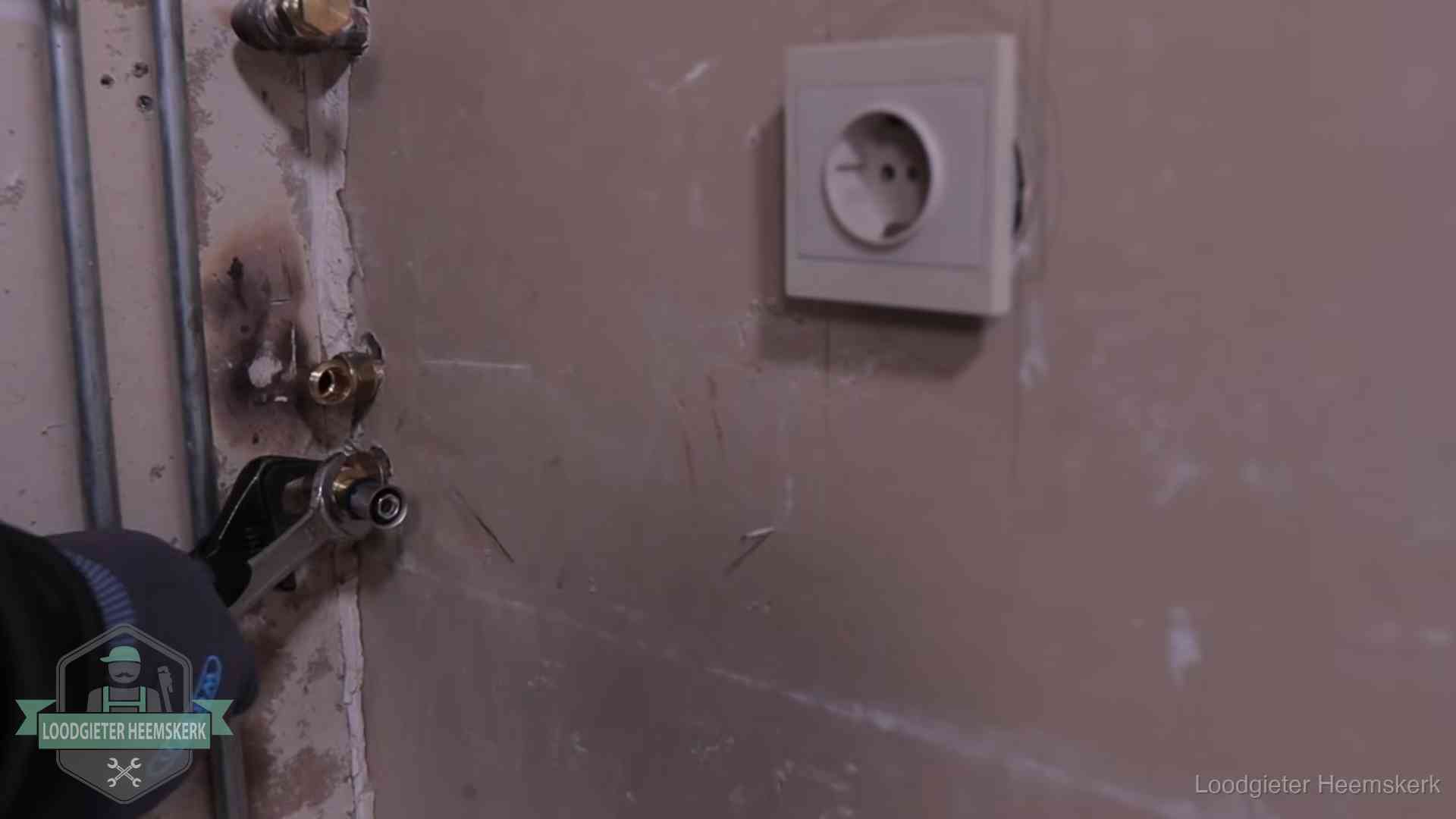 Monteur draait een perskoppeling vast op een leidingaansluiting in Heemskerk