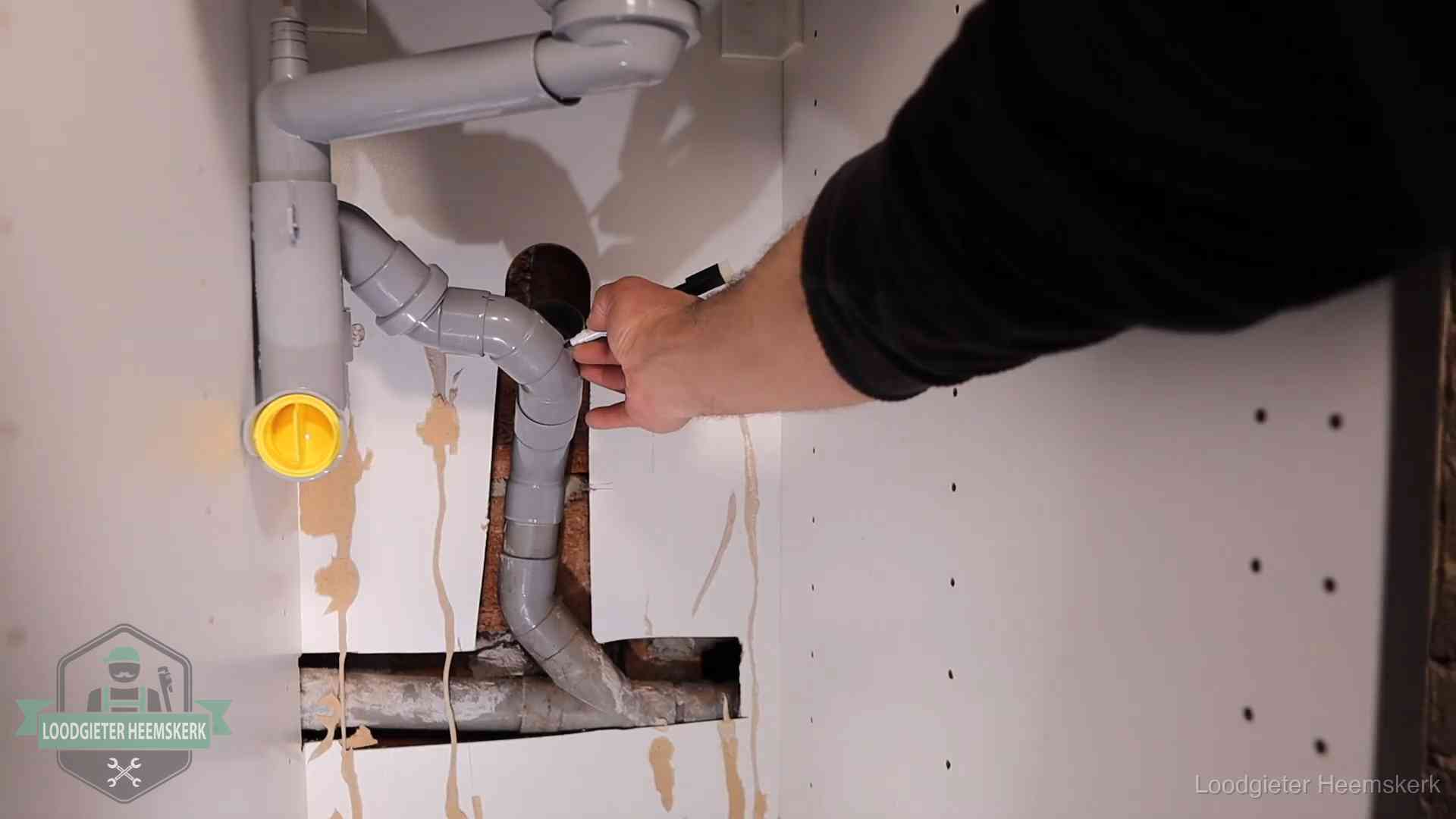 Loodgieter markeert een pvc-afvoerbuis onder een gootsteen in Heemskerk