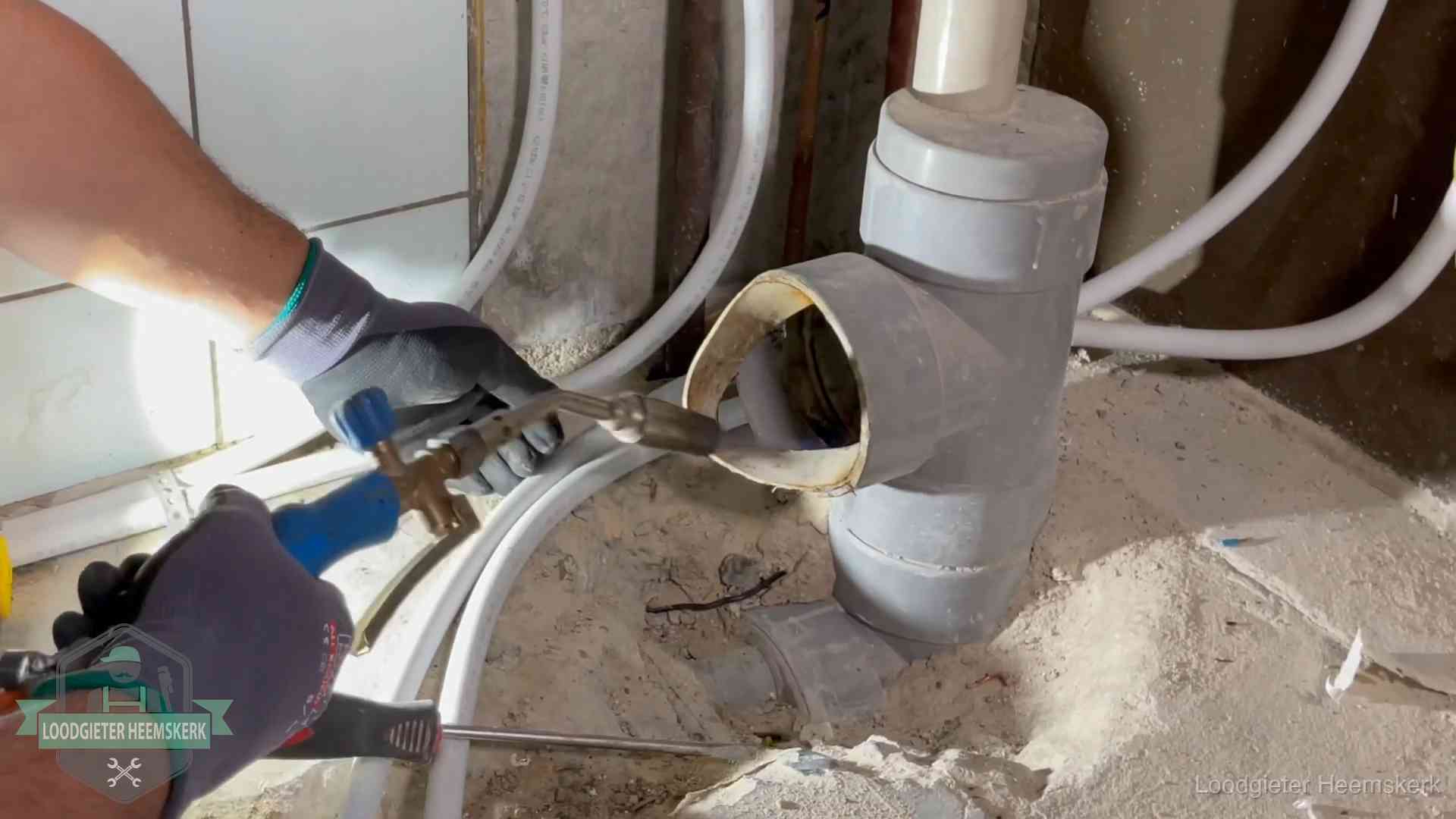 Loodgieter werkt met brander en messing kraanwerk aan leidingen in Heemskerk