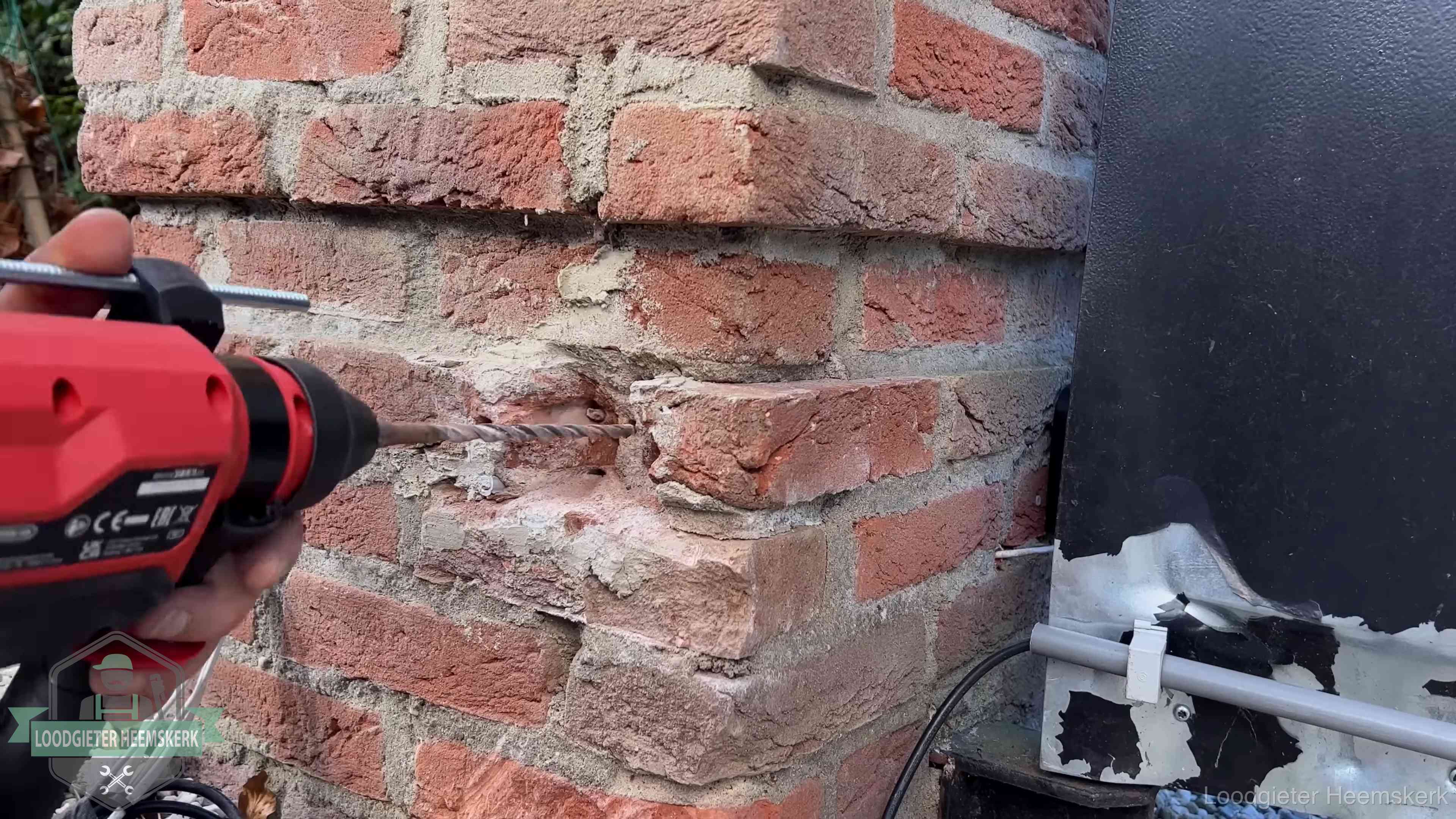 Vakman boort in de buitenmuur van een woning in de regio Heemskerk