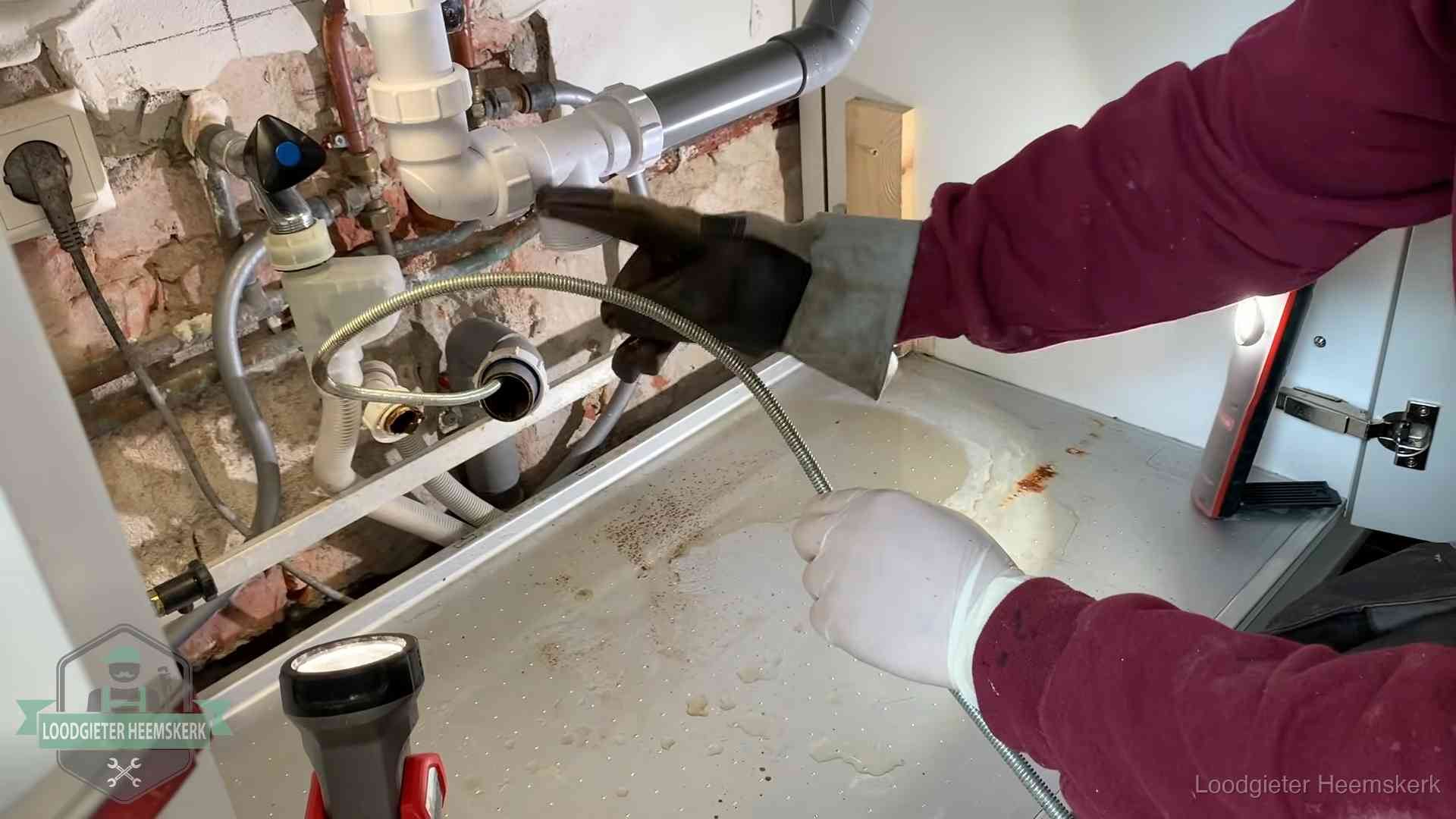 Spiraal of hogedruk in Heemskerk Ontstoppingsveer gaat in een geopende sifonaansluiting onder het aanrecht in Heemskerk
