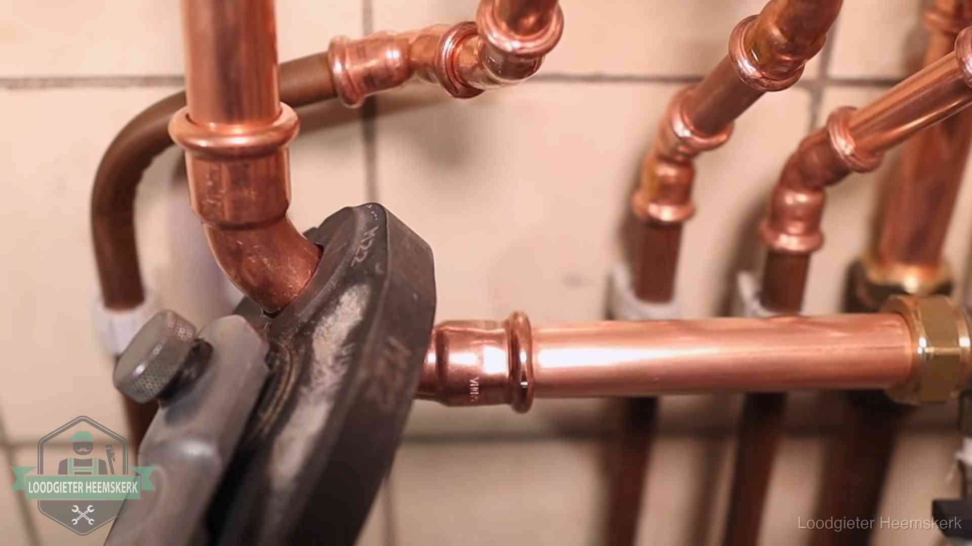 Persmachine perst een koperen fitting op nieuw leidingwerk in Heemskerk