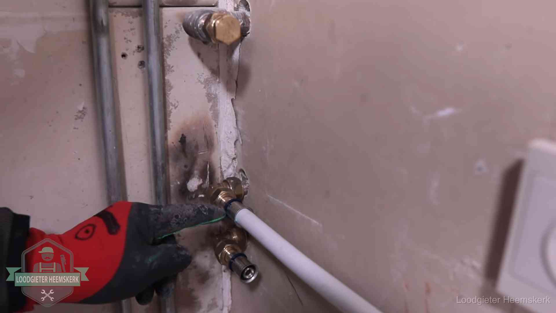Loodgieter wijst de persfitting op nieuwe muuraansluitingen aan in een woning in Heemskerk