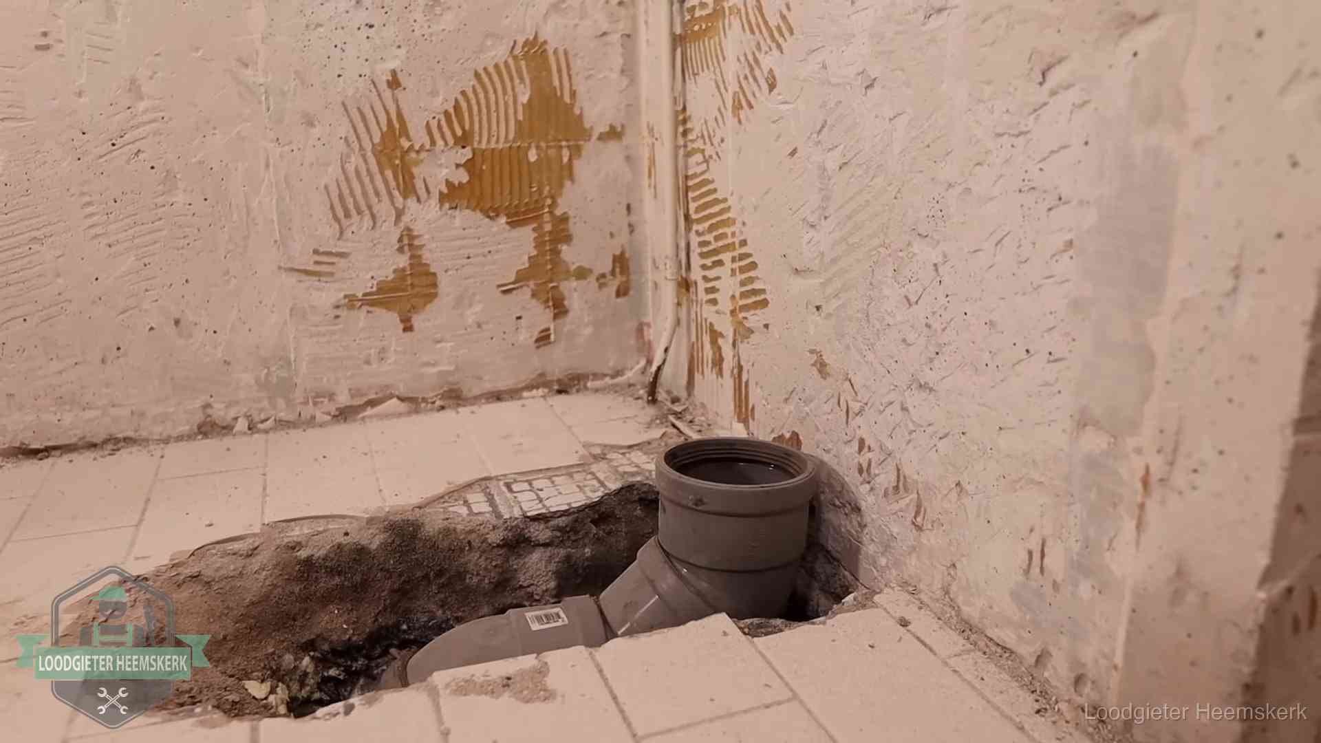 Verzakt riool herstellen in Heemskerk Opengebroken vloer met een nieuwe pvc-rioolbocht in een gegraven sleuf in Heemskerk