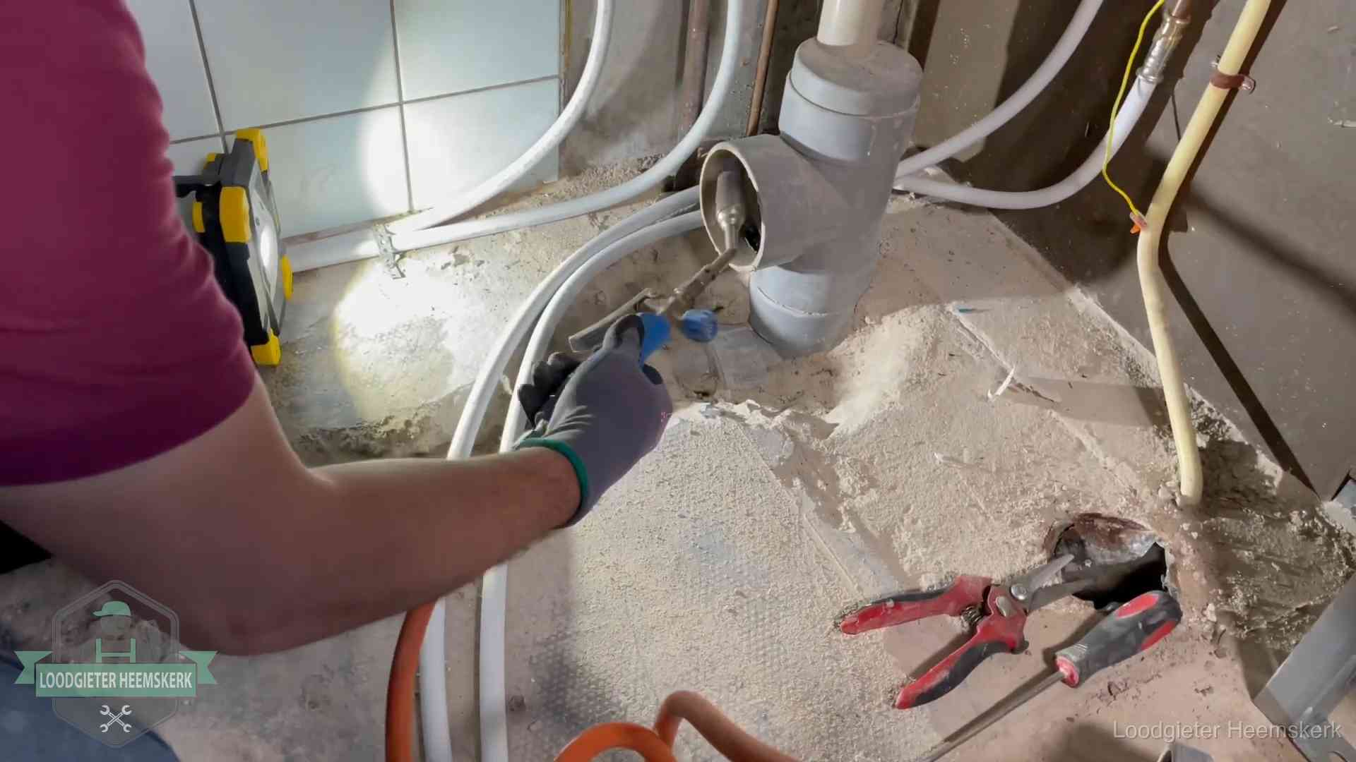 Loodgieter werkt aan leidingen bij een pvc-standleiding in een appartement in Heemskerk