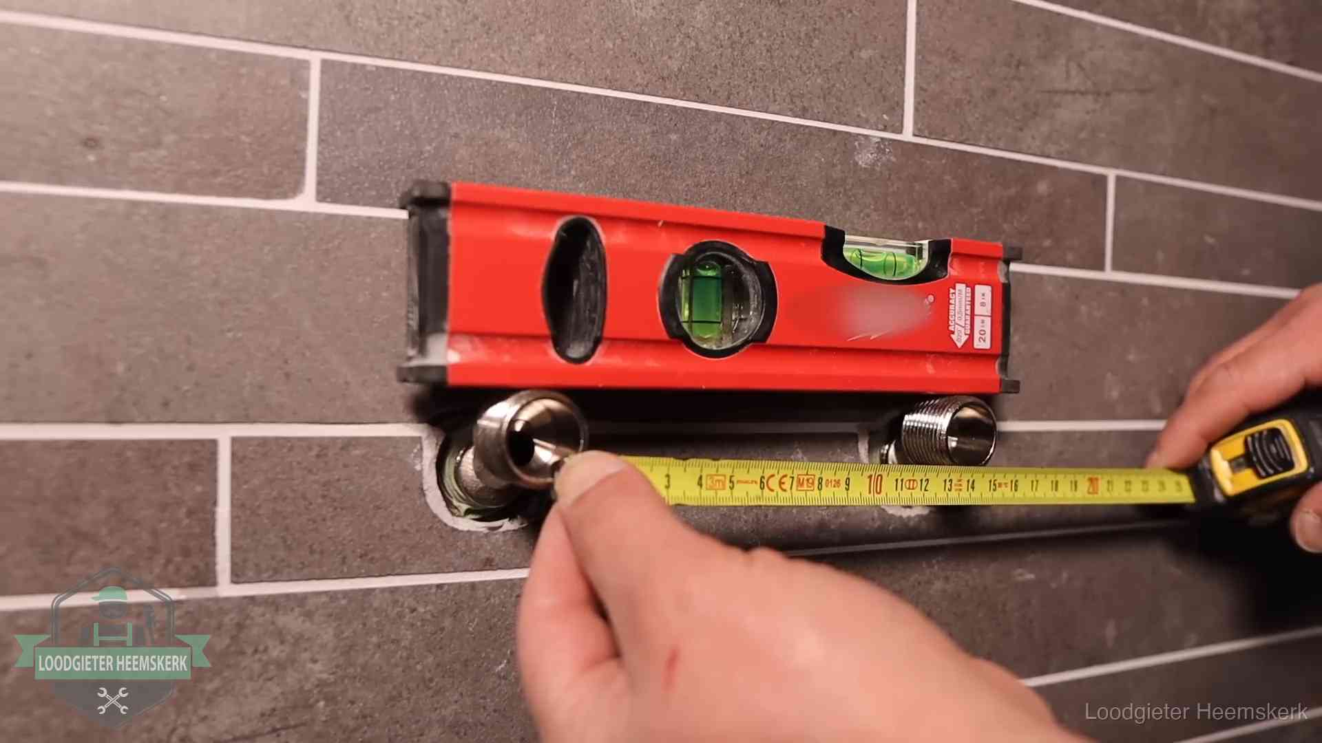 Waterpas en duimstok bij kraan-aansluitpunten in een badkamer in Heemskerk