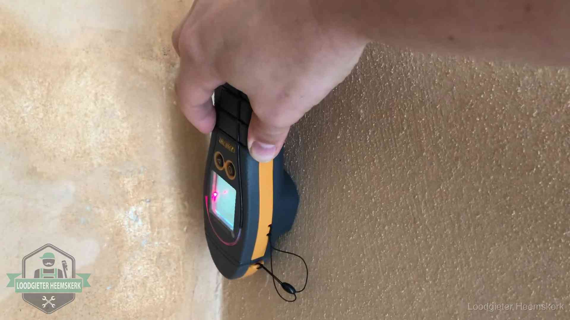 Vochtmeter tegen een muur met vochtplekken tijdens het opsporen van een daklekkage in Heemskerk